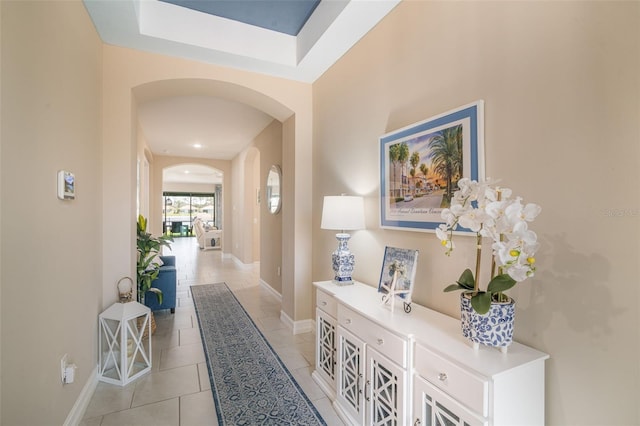 629 Ibiza Loop, Venice, FL 34292 - hallway featuring arched walkways, light tile patterned floors, and baseboards