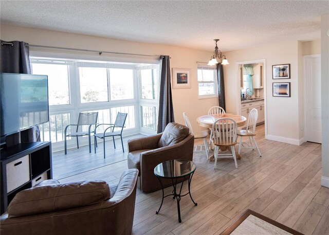 1255 Tarpon Center Dr Unit 604, Venice, FL 34285 - living area with a chandelier, light wood-style flooring, a textured ceiling, and baseboards