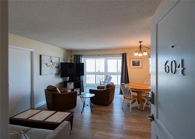 1255 Tarpon Center Dr Unit 604, Venice, FL 34285 - living room featuring hardwood / wood-style flooring, a textured ceiling, and a chandelier