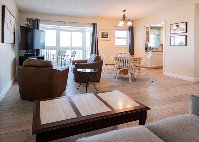 1255 Tarpon Center Dr Unit 604, Venice, FL 34285 - living area with baseboards, light wood-style floors, and a chandelier