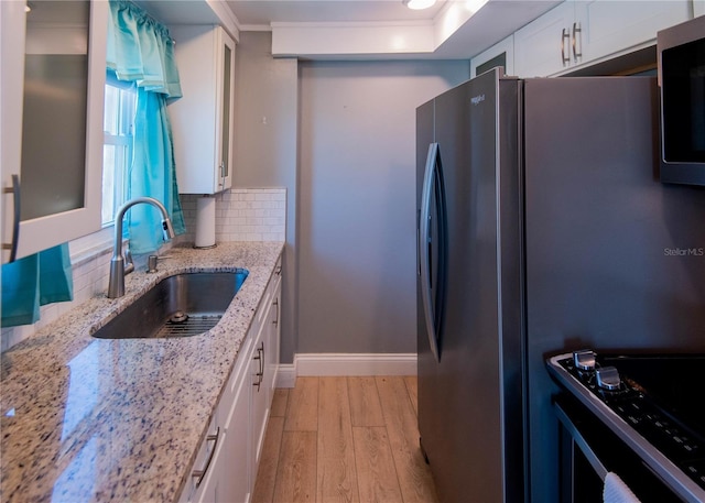 1255 Tarpon Center Dr Unit 604, Venice, FL 34285 - kitchen featuring appliances with stainless steel finishes, a sink, light wood-style flooring, white cabinetry, and backsplash