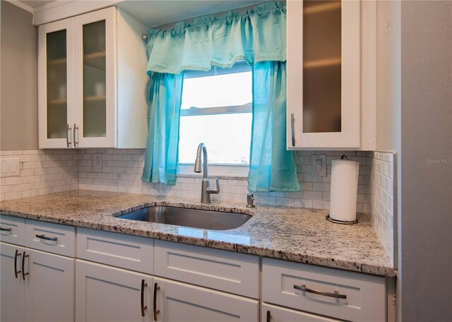 1255 Tarpon Center Dr Unit 604, Venice, FL 34285 - kitchen with a sink, decorative backsplash, white cabinets, and light stone countertops