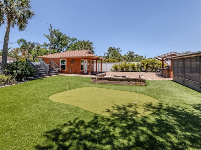 view of yard featuring an area to practice putting, a patio, a sunroom, and stairway