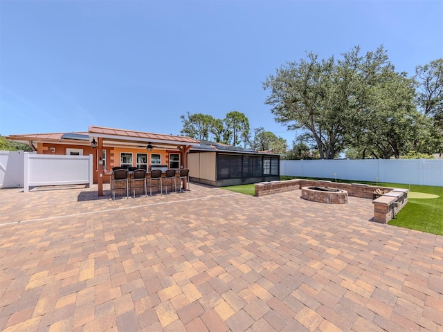 view of patio / terrace with a fire pit, a fenced backyard, a ceiling fan, and a sunroom