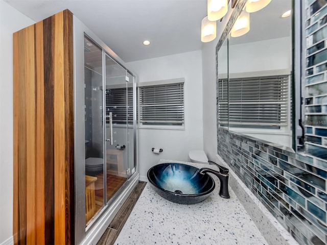 bathroom with toilet, a shower stall, baseboards, and recessed lighting