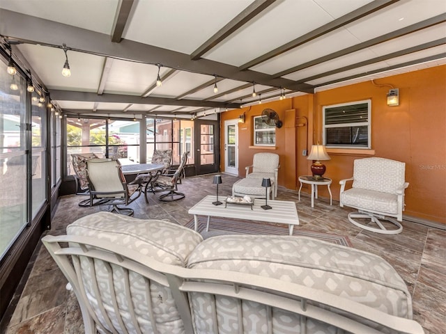 sunroom / solarium featuring beam ceiling and outdoor dining area