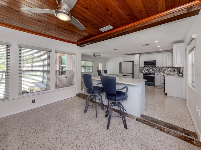 kitchen featuring appliances with stainless steel finishes, light countertops, dark speckled floor, a ceiling fan, and wooden ceiling