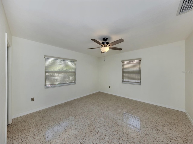 empty room with speckled floor, ceiling fan, and baseboards