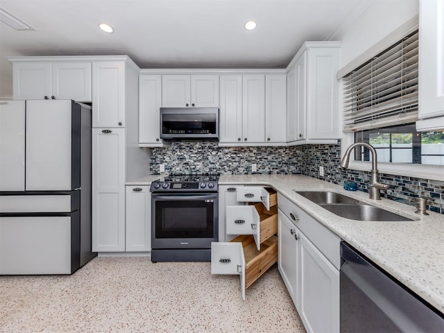 kitchen with stainless steel appliances, a sink, white cabinets, recessed lighting, and backsplash