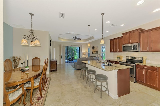 241 Marcheno Way, Nokomis, FL 34275 - kitchen featuring appliances with stainless steel finishes, recessed lighting, light stone counters, open floor plan, and a tray ceiling