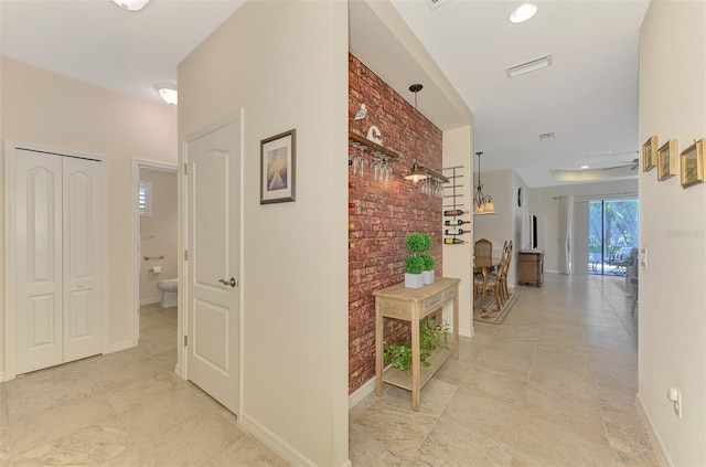 241 Marcheno Way, Nokomis, FL 34275 - corridor with brick wall, baseboards, and light tile patterned floors