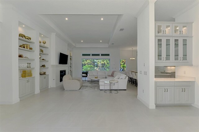 9048 Luna Ln, Sarasota, FL 34241 - living room with built in shelves, a glass covered fireplace, recessed lighting, light tile patterned flooring, and ornamental molding