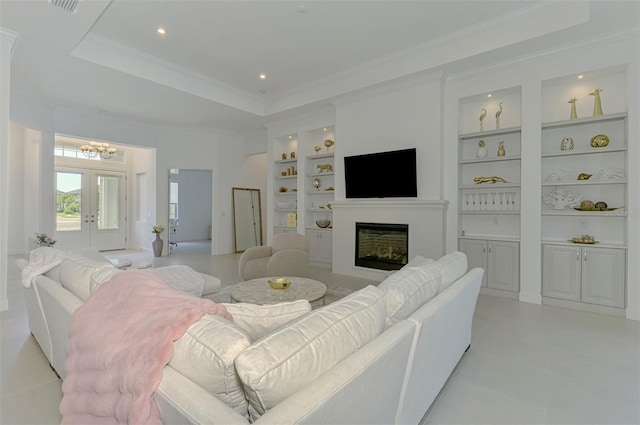 9048 Luna Ln, Sarasota, FL 34241 - living room featuring built in shelves, a glass covered fireplace, a chandelier, light tile patterned flooring, and a tray ceiling
