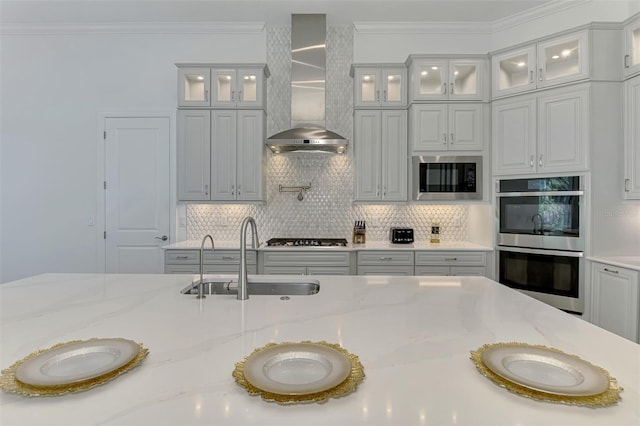 9048 Luna Ln, Sarasota, FL 34241 - kitchen featuring a sink, wall chimney range hood, stainless steel appliances, tasteful backsplash, and light stone countertops