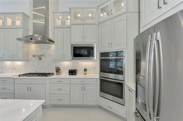 9048 Luna Ln, Sarasota, FL 34241 - kitchen featuring appliances with stainless steel finishes, wall chimney range hood, tasteful backsplash, and light tile patterned floors
