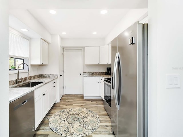 1439 Strada D Argento, Venice, FL 34292 - kitchen with stainless steel appliances, a sink, light wood finished floors, white cabinets, and light stone countertops