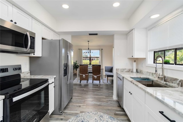 1439 Strada D Argento, Venice, FL 34292 - kitchen featuring stainless steel appliances, white cabinets, light wood-style flooring, light stone counters, and recessed lighting