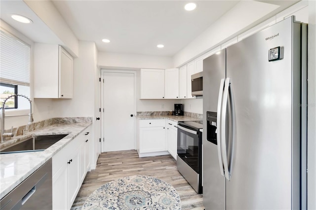 1439 Strada D Argento, Venice, FL 34292 - kitchen with stainless steel appliances, white cabinets, light wood-style floors, recessed lighting, and light stone counters