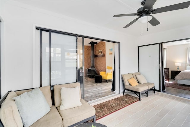 1439 Strada D Argento, Venice, FL 34292 - bedroom featuring light wood-style flooring, multiple windows, a wood stove, and a ceiling fan