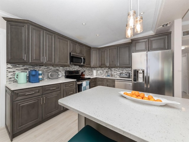 161 Suntan Ave, Sarasota, FL 34237 - kitchen featuring stainless steel appliances, dark brown cabinetry, decorative backsplash, light wood-style floors, and hanging light fixtures