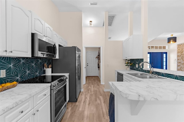 2424 Affinity Ln, North Port, FL 34286 - kitchen with stainless steel appliances, a sink, white cabinetry, backsplash, and light wood-type flooring