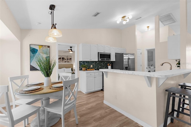 2424 Affinity Ln, North Port, FL 34286 - kitchen with appliances with stainless steel finishes, a kitchen bar, white cabinets, backsplash, and a peninsula