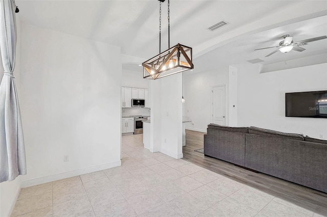 unfurnished living room featuring light tile patterned floors, ceiling fan, baseboards, and a chandelier