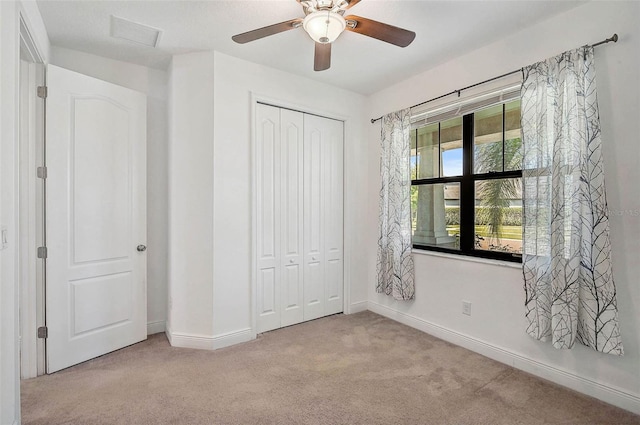unfurnished bedroom with carpet flooring, a closet, baseboards, and a ceiling fan