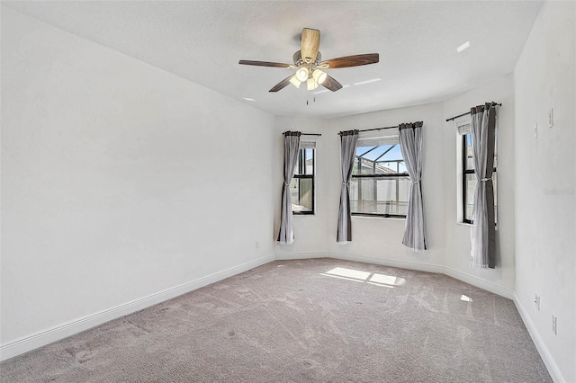 carpeted empty room featuring baseboards and a ceiling fan