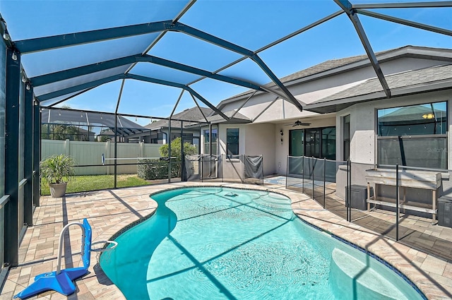 view of swimming pool with a patio area, a ceiling fan, fence, and glass enclosure