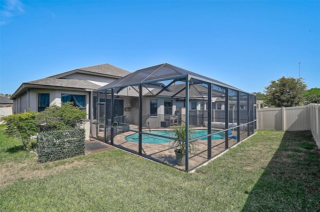 back of property with a patio area, a shingled roof, and glass enclosure