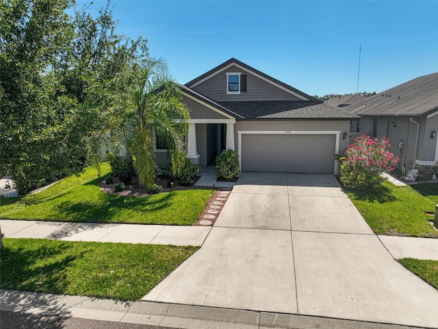 view of front of property with a garage, a front yard, driveway, and a shingled roof