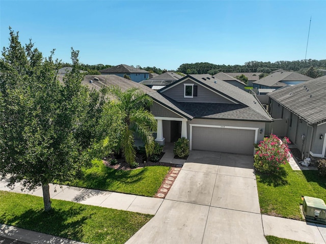 view of front facade featuring an attached garage, a shingled roof, driveway, a front lawn, and a residential view