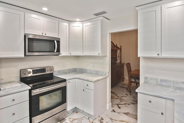 27416 Natal Dr, Punta Gorda, FL 33983 - kitchen with appliances with stainless steel finishes, light marble finish floors, light countertops, recessed lighting, and white cabinets