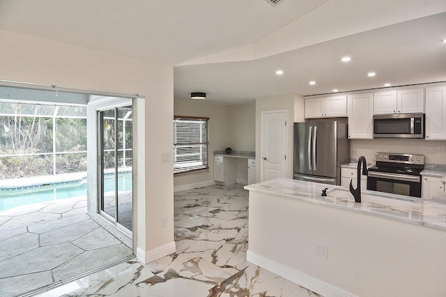 27416 Natal Dr, Punta Gorda, FL 33983 - kitchen with stainless steel appliances, baseboards, recessed lighting, white cabinets, and light marble finish floors