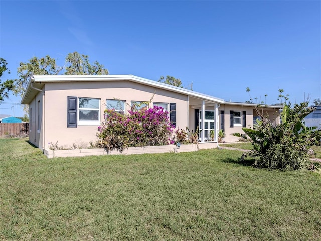6231 Jordan St, North Port, FL 34287 - rear view of house featuring stucco siding and a lawn