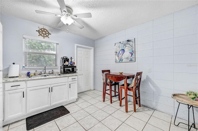 422 Polk Ave, Cape Canaveral, FL 32920 - kitchen featuring a sink, a textured ceiling, a ceiling fan, white cabinetry, and tile walls