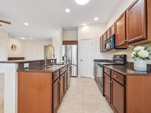 1493 Maseno Dr, Venice, FL 34292 - kitchen featuring black appliances, a sink, dark stone countertops, light tile patterned floors, and a kitchen island with sink