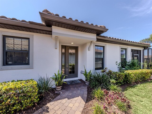 5853 Semolino St, Nokomis, FL 34275 - doorway to property featuring stucco siding and a tile roof