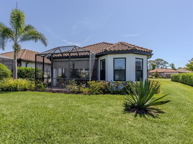 5853 Semolino St, Nokomis, FL 34275 - back of house with a tiled roof, stucco siding, a yard, and a lanai