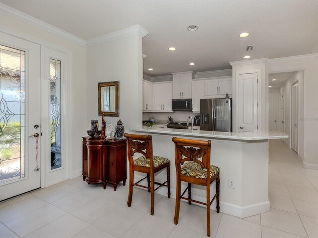5853 Semolino St, Nokomis, FL 34275 - kitchen with appliances with stainless steel finishes, a peninsula, a kitchen bar, white cabinets, and recessed lighting
