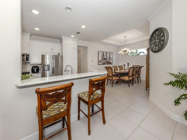 5853 Semolino St, Nokomis, FL 34275 - kitchen featuring stainless steel appliances, ornamental molding, baseboards, white cabinets, and a kitchen breakfast bar