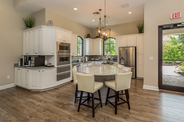 5853 Semolino St, Nokomis, FL 34275 - kitchen with stainless steel appliances, white cabinetry, decorative backsplash, a sink, and a chandelier