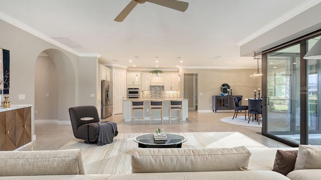 1481 Hyssop Loop, North Port, FL 34289 - living area featuring ceiling fan, crown molding, baseboards, arched walkways, and light tile patterned floors