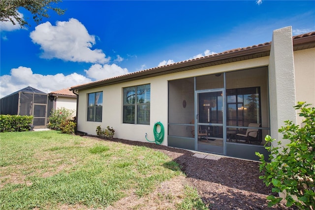1438 Maseno Dr, Venice, FL 34292 - rear view of property featuring a sunroom, stucco siding, a lawn, and a tiled roof