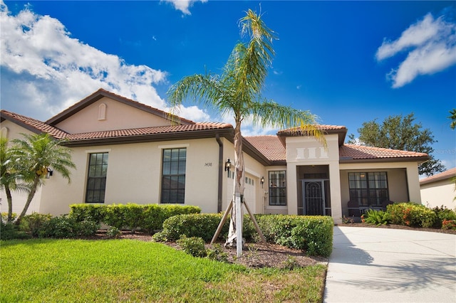 1438 Maseno Dr, Venice, FL 34292 - mediterranean / spanish-style home with an attached garage, stucco siding, a front yard, and a tile roof