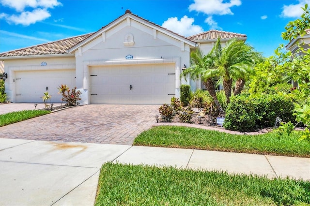 21649 Avon Park Ct, Venice, FL 34293 - view of front facade with decorative driveway, a tile roof, a garage, and stucco siding