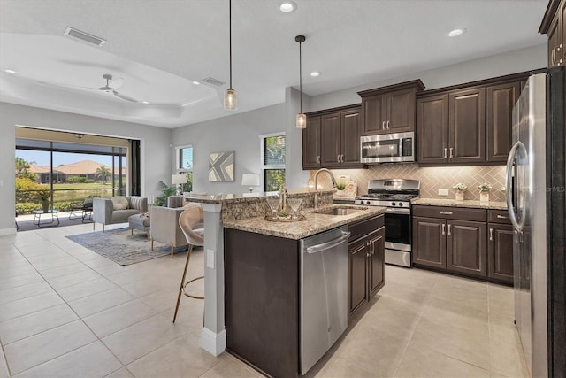 21649 Avon Park Ct, Venice, FL 34293 - kitchen featuring appliances with stainless steel finishes, a sink, open floor plan, tasteful backsplash, and a breakfast bar