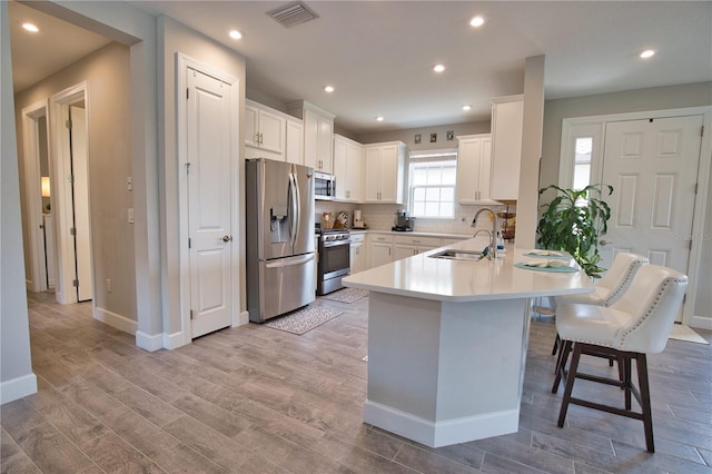 10410 Inglenook Ter, Palmetto, FL 34221 - kitchen with appliances with stainless steel finishes, a sink, a peninsula, a kitchen bar, and light wood-style flooring