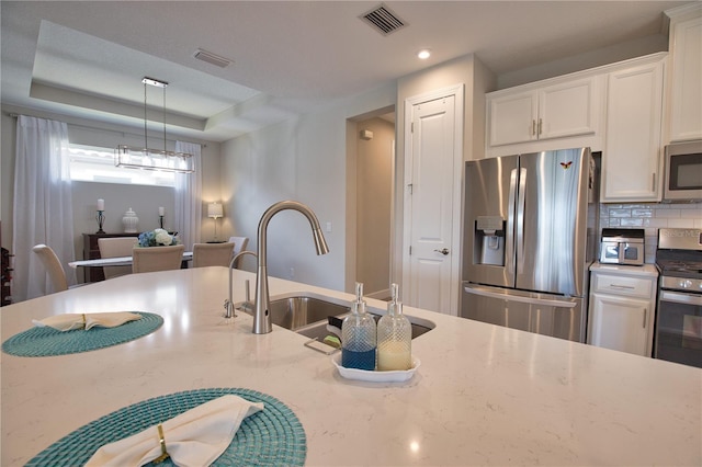 10410 Inglenook Ter, Palmetto, FL 34221 - kitchen featuring stainless steel appliances, white cabinetry, a sink, decorative light fixtures, and tasteful backsplash